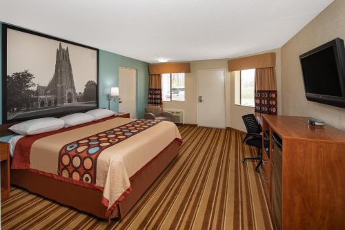 a hotel room with a bed and a flat screen tv at Super 8 by Wyndham Burlington NC in Burlington