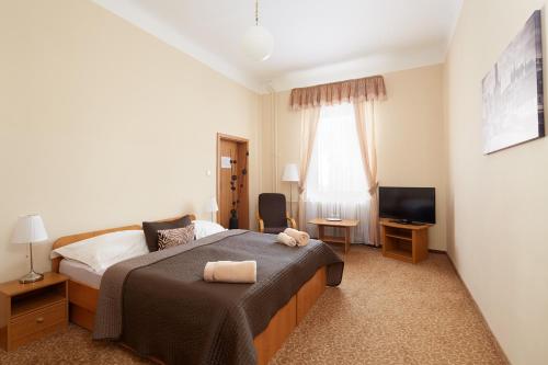 a bedroom with a bed, chair, desk and a television at Hotel City Bell in Prague