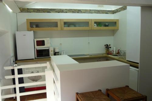 une cuisine avec des armoires blanches et un réfrigérateur blanc dans l'établissement La Maison Bleue d'Ardèche, à Saint-Mélany