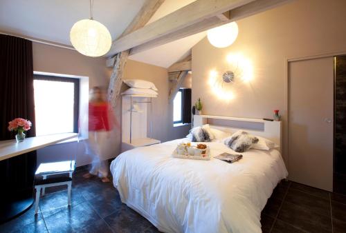 a woman standing in a bedroom with a bed at Urban Style LES FLEURINES in Villefranche-de-Rouergue