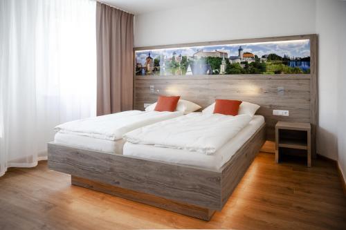 ein Schlafzimmer mit einem großen Bett und einem Gemälde an der Wand in der Unterkunft Hotel Ertl in Kulmbach