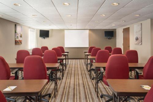 a classroom with red chairs and tables and a whiteboard at Super 8 by Wyndham Chambersburg I-81 in Chambersburg