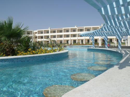 a swimming pool with a chair and a building at Royal Brayka Beach Resort in Abu Dabab