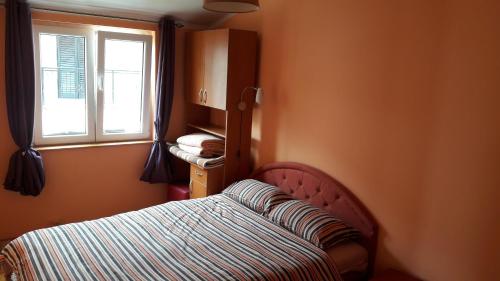 a small bedroom with a bed and a window at Porodicni apartman in Herceg-Novi