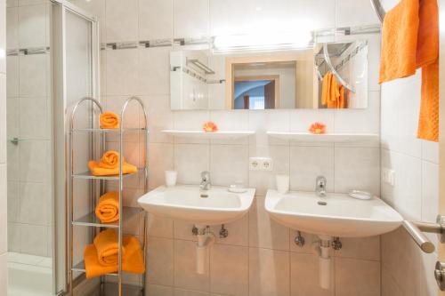 a bathroom with two sinks and a shower with orange towels at Apart Hofer in Nauders