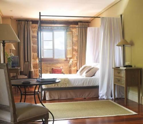 a bedroom with a bed and a desk and a window at Narbasu Restaurante y Hotel in Cereceda