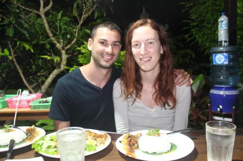 a man and a woman sitting at a table with plates of food at Summer Homestay Bali in Nusa Dua