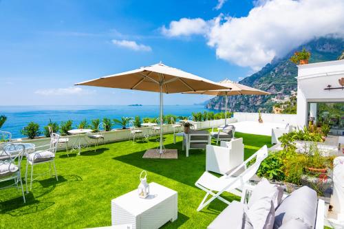 
a patio area with chairs, tables and umbrellas at Villa Pietra Santa in Positano
