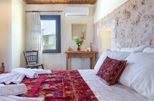 a bedroom with a bed and a chair and a window at Smaragda Stone Villa in Vamos