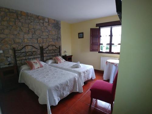 a bedroom with two beds and a stone wall at El Pedroso in Santillana del Mar