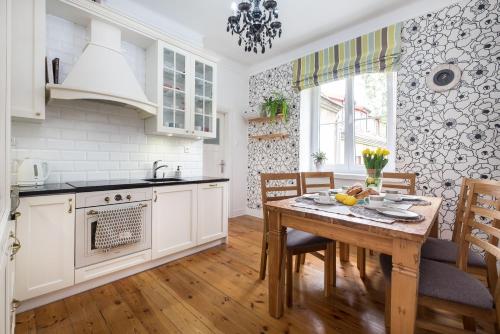 une cuisine avec des armoires blanches et une table en bois dans l'établissement Prosta Apartment Old Town, à Olsztyn