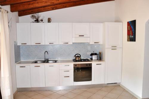 Biała kuchnia z białymi szafkami i zlewem w obiekcie Villa Niko w mieście Costa Paradiso
