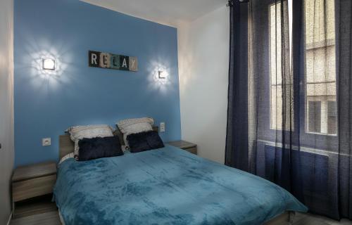 a blue bedroom with a bed and a window at Paradis Doré in LʼIsle-sur-la-Sorgue