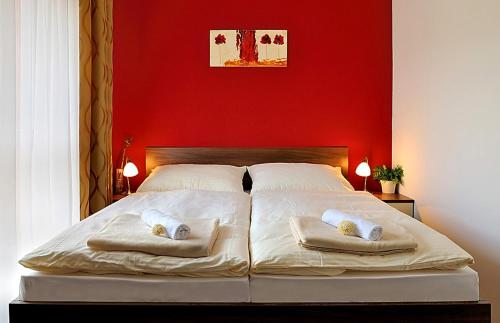 a bedroom with a red wall and a bed with two pillows at Melrose Apartments in Bratislava