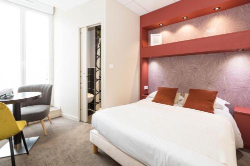 a bedroom with a bed and a desk and a chair at Cit'Hotel Les Alizes in Dinard