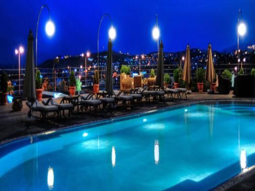 a swimming pool with tables and chairs at night at Lvzz Hotel in Bodrum City