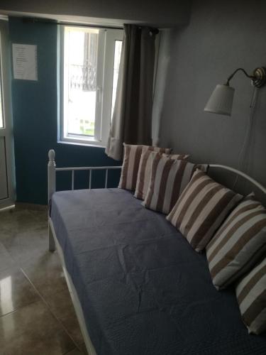 a bedroom with a bed with pillows and a window at Castle By The Sea in Artemida