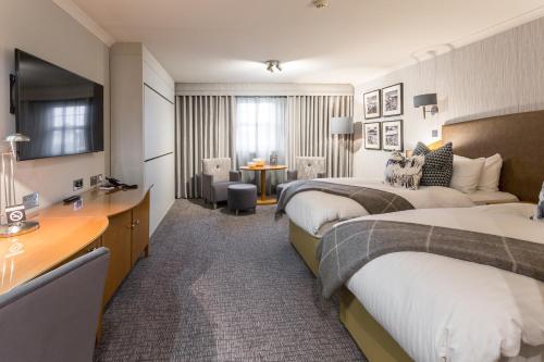 a hotel room with two beds and a desk at Auchrannie Resort in Brodick