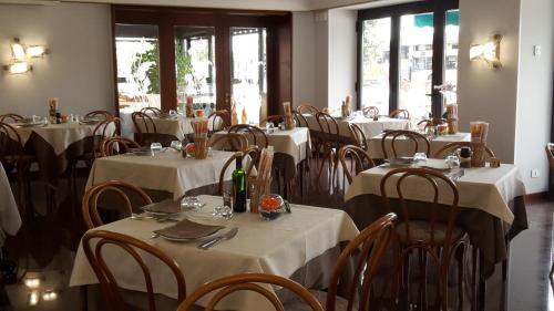 a restaurant with white tables and chairs and windows at Hotel Belvedere in Venice-Lido
