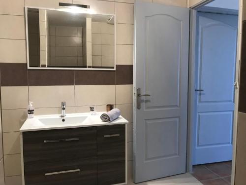ein Badezimmer mit einem Waschbecken, einem Spiegel und einer Tür in der Unterkunft A casa nostra in Biguglia