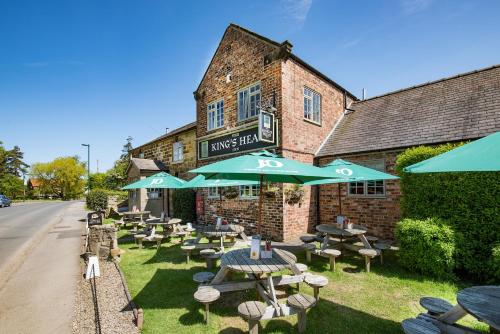 un grupo de mesas y sillas con sombrillas frente a un edificio en The King's Head Inn - The Inn Collection Group, en Great Ayton