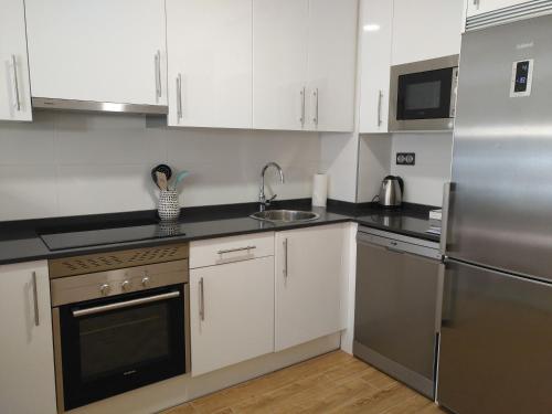 a kitchen with white cabinets and a stainless steel refrigerator at Apartamento Playa Poniente in Gijón