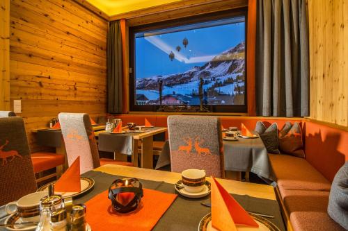 a restaurant with tables and chairs and a large window at Hotel Garni Haus Tyrol in Obertauern