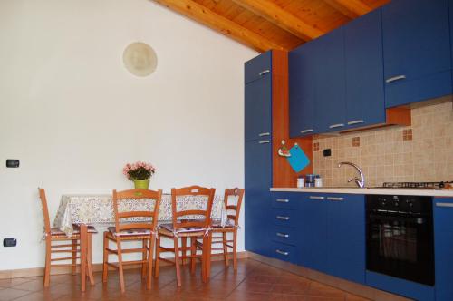 een keuken met blauwe kasten en een tafel met stoelen bij Portorosa Apartments Helene in Furnari