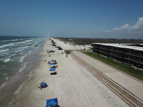 a beach with chairs and umbrellas and the ocean at Island House BeachFront Condo Hotel in Corpus Christi