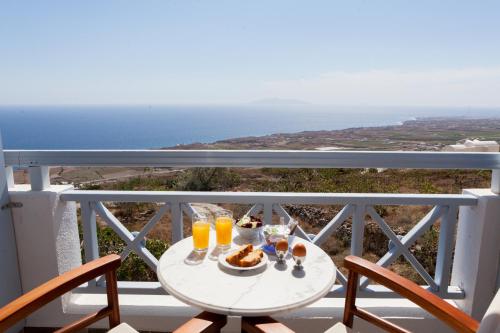 a table with food and drinks on a balcony with the ocean at Luna Rossa Santorini in Imerovigli