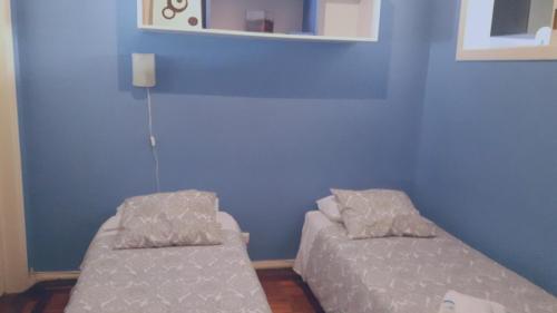 two beds in a room with a blue wall at Apartamento Lisboa-Alameda in Lisbon