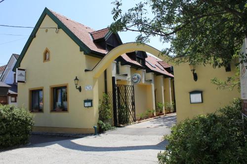 a yellow building with an arch in front of it at Levanda Panzió in Kópháza