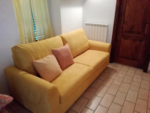 a yellow couch with two pillows on it in a room at Fattoria di Rigone in Coltavolino