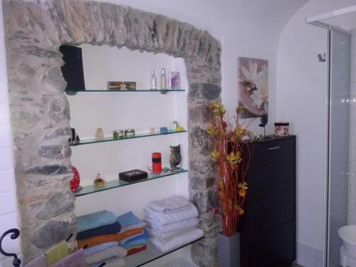 ein Badezimmer mit einer Steinmauer mit Regalen und Handtüchern in der Unterkunft La Casina Di Jessica in Aulla