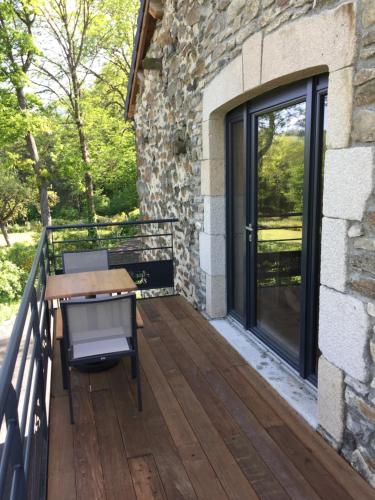 a wooden deck with a table and a door at Aux Pays Des Sucs in Saint-Hostien