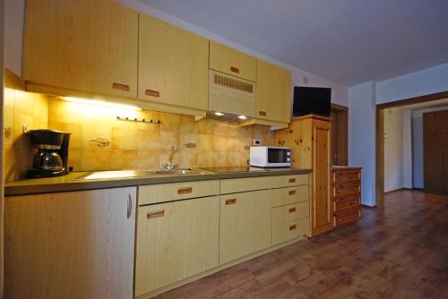 a kitchen with wooden cabinets and a sink and a microwave at Piz da Cir in Colfosco