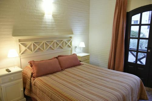 a bedroom with a bed with two lamps and a window at Apart Hotel Las Hadas Carilo in Carilo