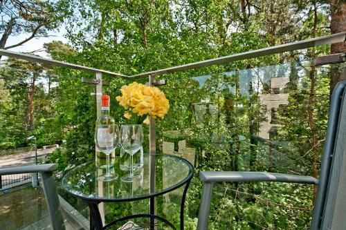 a glass table with a bottle of wine and a yellow flower at Villa Aqua BlueApart Jurata in Jurata
