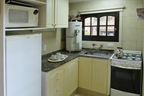 a kitchen with a sink and a stove and a microwave at Apart Hotel Las Hadas Carilo in Carilo
