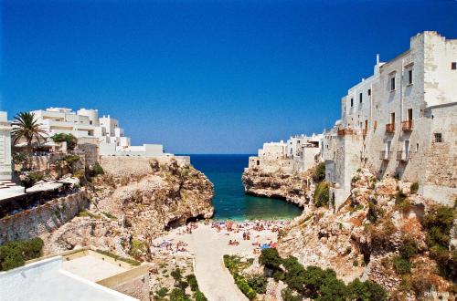 a group of people standing on a beach next to the ocean at Torres Suite in Polignano a Mare