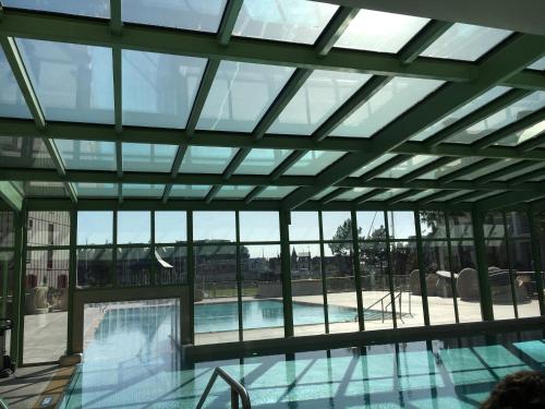 une grande piscine avec un grand plafond en verre dans l'établissement Cyrille et Vacances Presqu'ile de la Touques, à Deauville