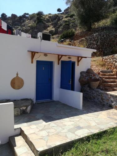 a white house with blue doors and stairs at Oasis Hotel Loutro in Loutro