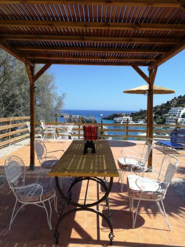 a table and chairs on a deck with a view of the water at Oasis Hotel Loutro in Loutro