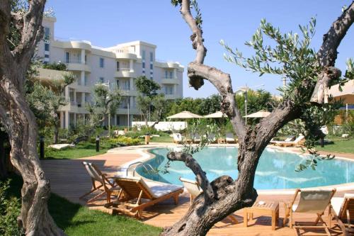 a resort with a pool and chairs and a building at Ibis Styles Bari Giovinazzo in Giovinazzo
