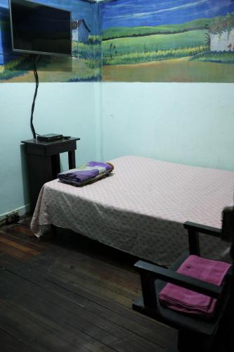 une chambre avec un lit, une télévision et une chaise dans l'établissement Hostal del Este Santa Fe, à San José