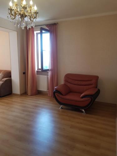 a living room with a red chair and a chandelier at Isani Panorama in Tbilisi City