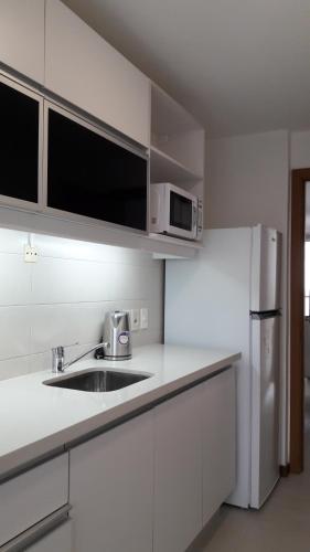a white kitchen with a sink and a refrigerator at Apart Altos del Virrey in Colonia del Sacramento