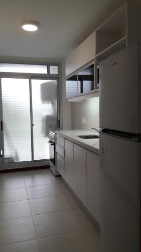 a kitchen with white appliances and a large window at Apart Altos del Virrey in Colonia del Sacramento