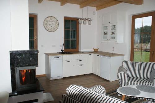 a living room with a kitchen and a fireplace at Lavender Cottage in Charzykowy