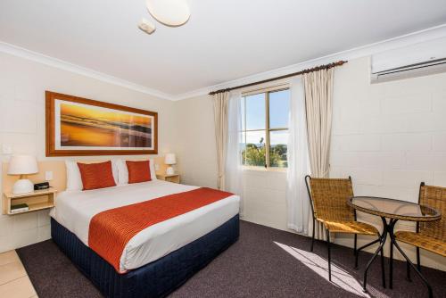 a bedroom with a bed and a table and a window at Soldiers Motel in Mudgee